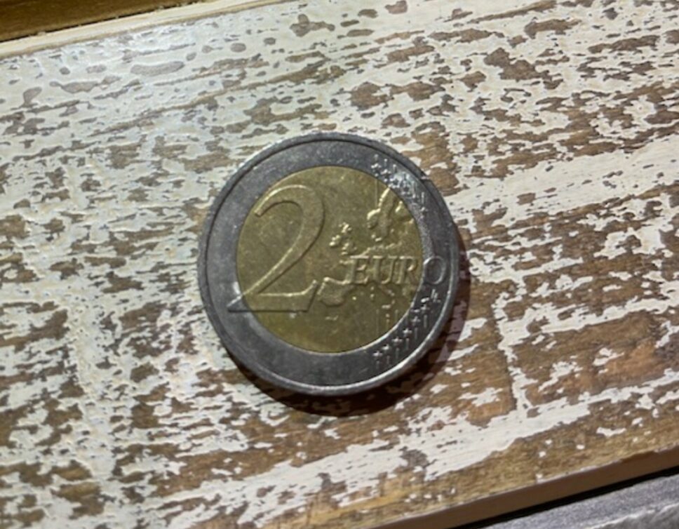 Estimation de la valeur monétaire et médaille de la pièce de 2 EUR avec un petit bonhomme en relief.